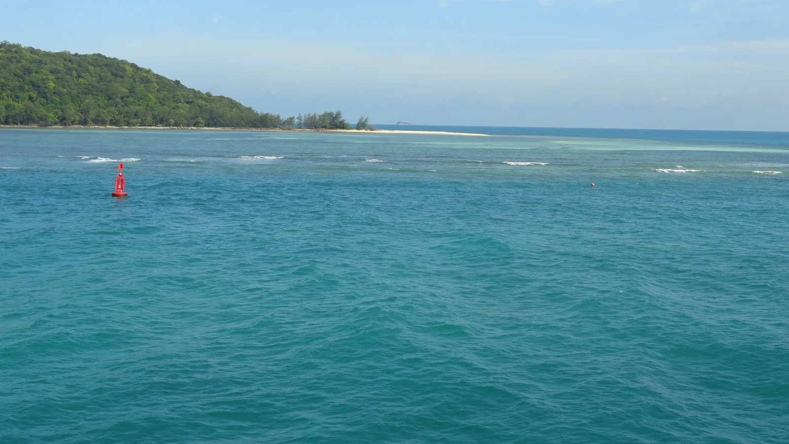 Turquoise sea and a wooded shore seen during the Samui–Phangan–Tao ferry journey