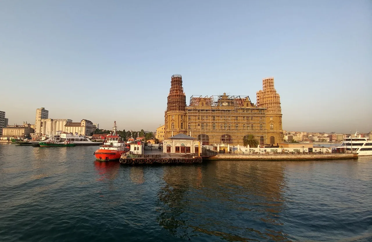 Boats and a historic waterfront building under restoration in Istanbul, Turkey